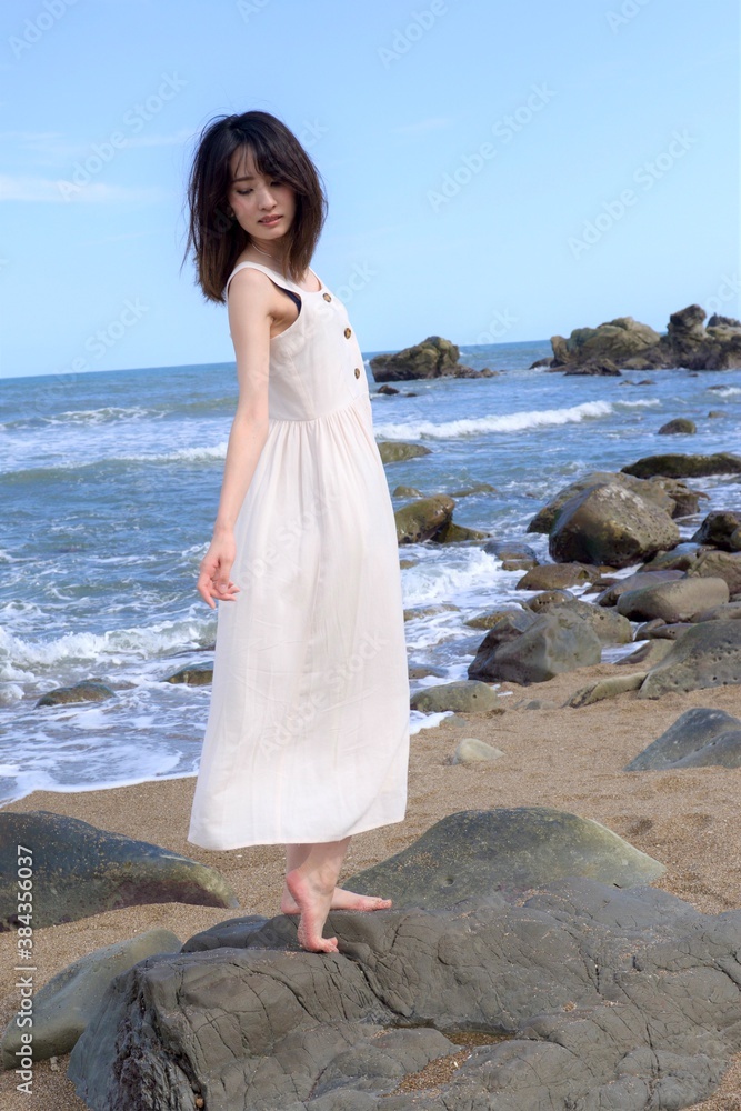 海岸でポーズをとる白いワンピース姿の若い女性 Stock Photo Adobe Stock