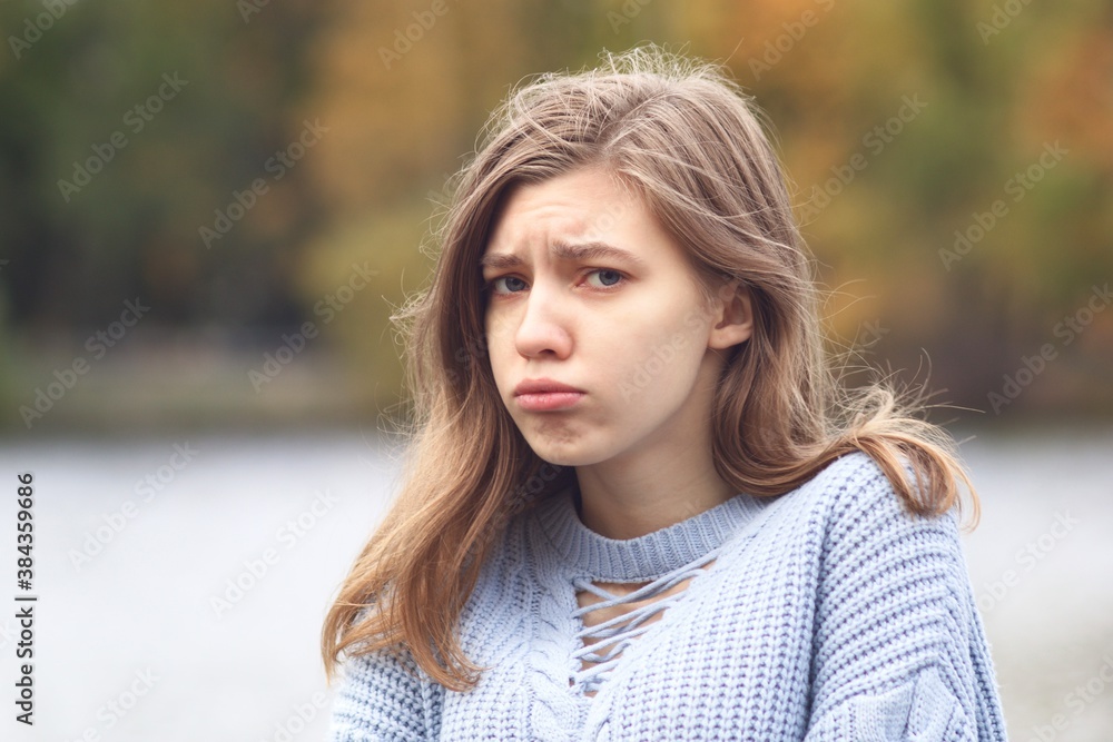 Portrait of sad upset offended young woman, frustrated teenager girl looking at camera with angry look outdoors at autumn park Portrait of sad upset offended young woman, frustrated teenager girl looking at camera with angry look outdoors at autumn park