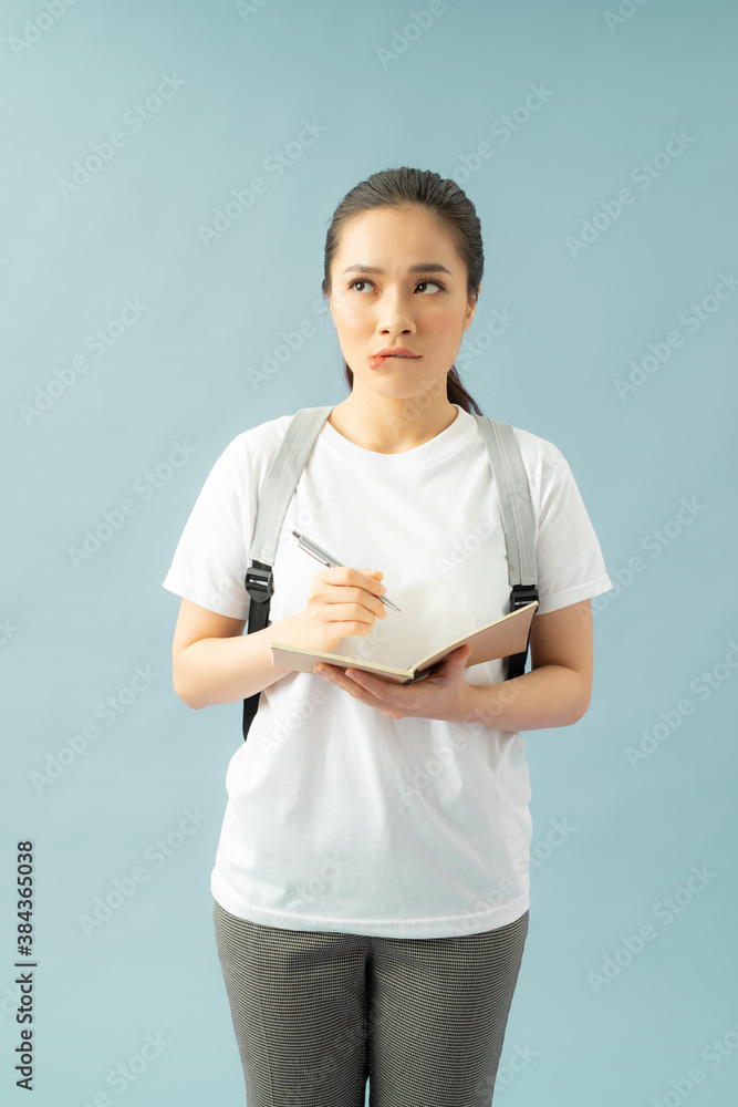 Puzzled indecisive troublesome college student frowns face in displeasure, diary in hands, thinks about writing new essay Puzzled indecisive troublesome college student frowns face in displeasure, diary in hands, thinks about writing new essay