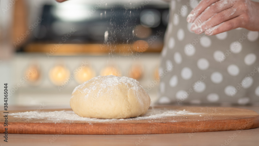 Knead dough, hand dough and flour close-up. A pastry chef in a grey polka-dot apron. Knead dough, hand dough and flour close-up. A pastry chef in a grey polka-dot apron.