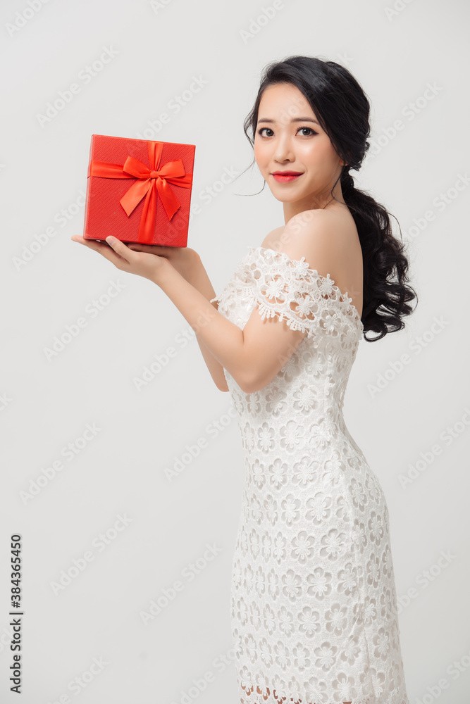 Happy beautiful young Asian woman holding gift box isolated over white background. Happy beautiful young Asian woman holding gift box isolated over white background.