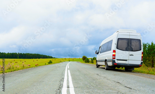 white tourist minibus close-up stands on the highway waiting for passengers. blurry focus
