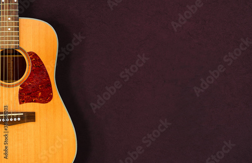 Acoustic guitar resting against a dark wall