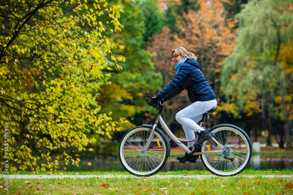 Fototapeta premium Urban biking - woman riding bicycle in city park 