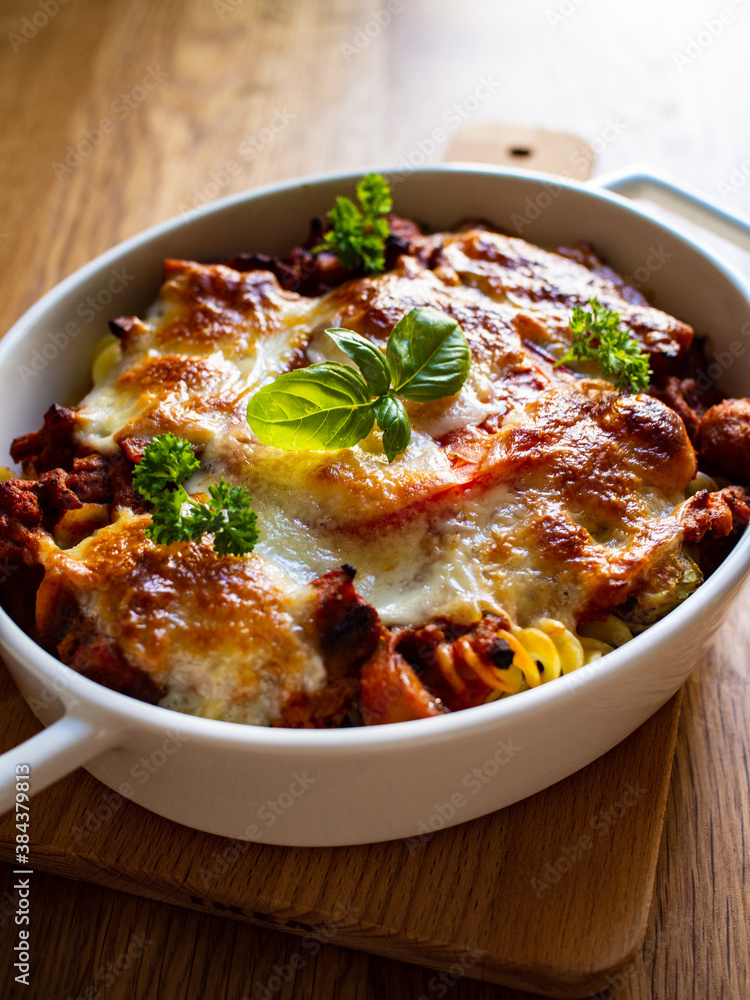 Pasta casserole with minced meat, mozzarella cheese and vegetables on wooden table Pasta casserole with minced meat, mozzarella cheese and vegetables on wooden table