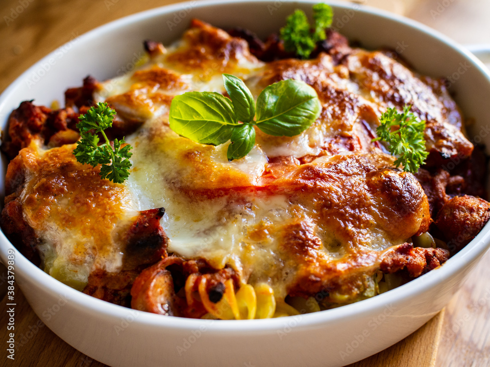 Pasta casserole with minced meat, mozzarella cheese and vegetables on wooden table Pasta casserole with minced meat, mozzarella cheese and vegetables on wooden table