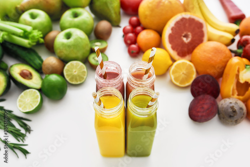 Composition of healthy detox juices and smoothies in bottles with paper straws, Various colorful fruits and vegetables isolated over white background