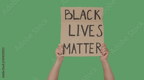 Female hands hold a poster from a cardboard box with the words BLACK LIVES MATTER. Protest against racism and police brutality. Isolated a green screen, chroma key. Close up. Slow motion. photo