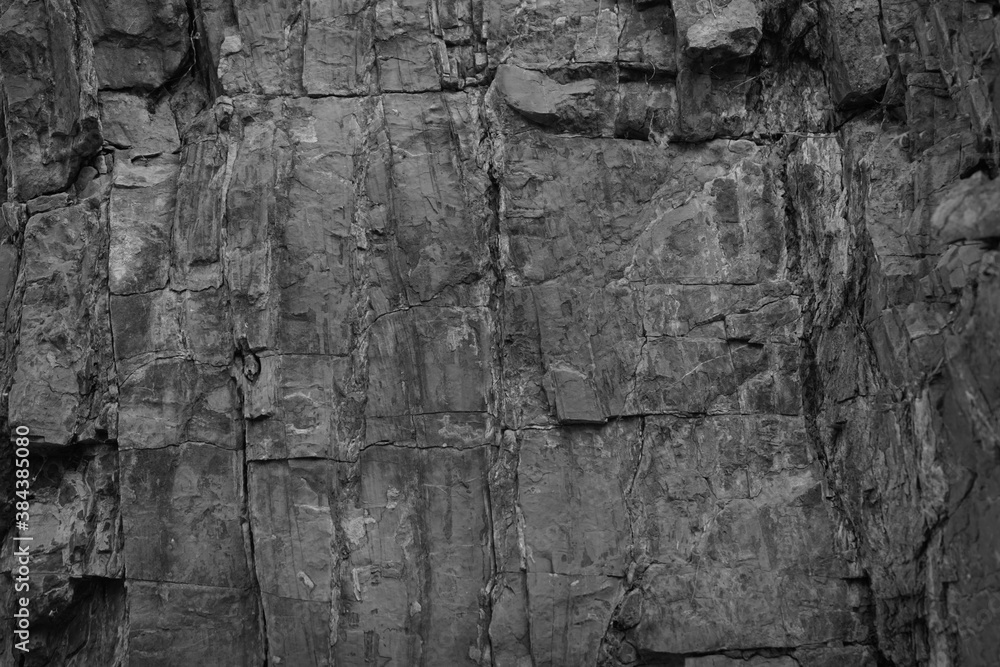 Dark grunge background. Black rock texture. Monochrome stone backdrop. Rough mountain surface. Close-up. Empty space.