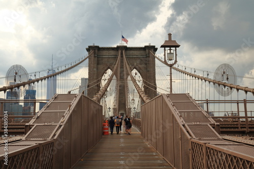 Tourists and residents cross Brooklyn Bridge in New York City, New York. Brooklyn Bridge is one of the oldest suspension bridges and was completed in 1883.