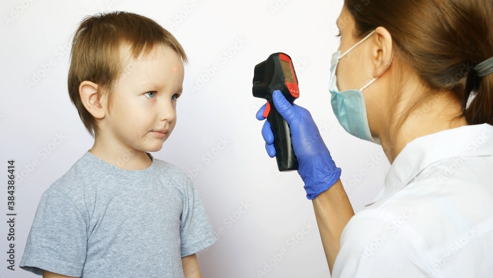 A woman doctor measures temperature of a little boy using a digital thermometer A woman doctor measures temperature of a little boy using a digital thermometer