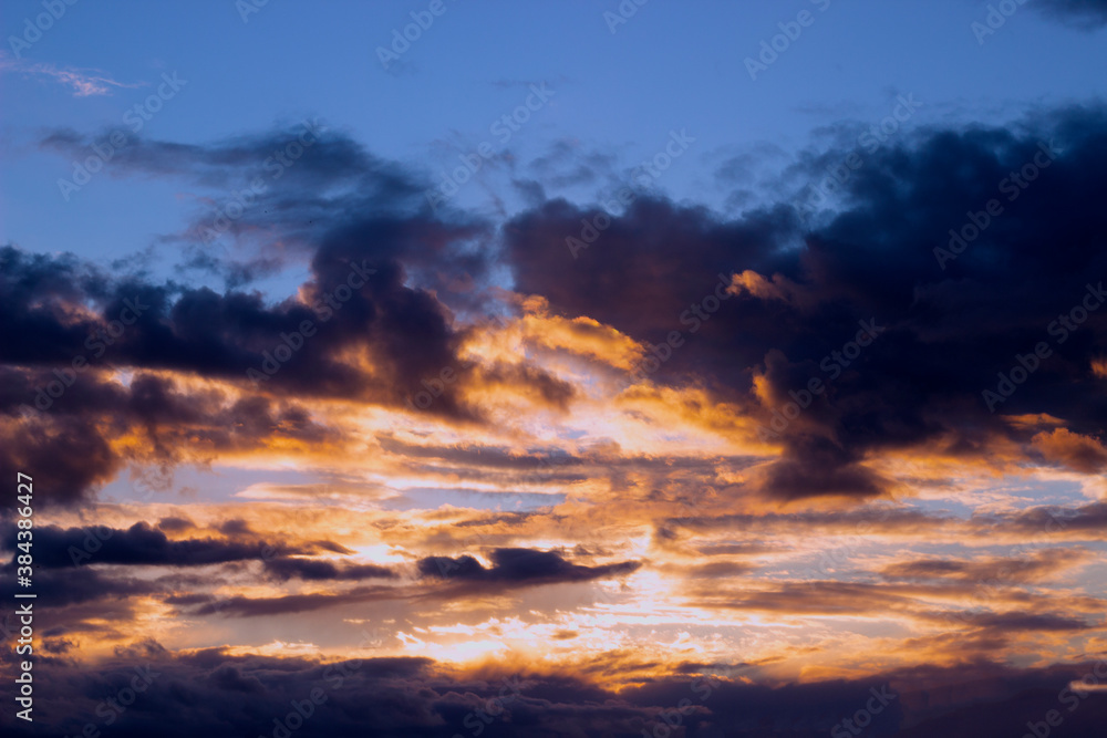 Obraz premium The sky before a thunderstorm. Golden sunlight against dark purple clouds.