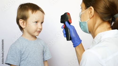 A woman doctor measures temperature of a little boy using a digital thermometer