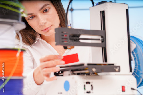 Young female designer working on a prototype device on a 3D printer