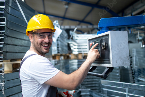 Portrait of factory worker operating industrial machine and setting parameters on the computer.