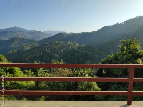 A crisp morning view of the hills from a balcony with red wooden fence © YellowCrest