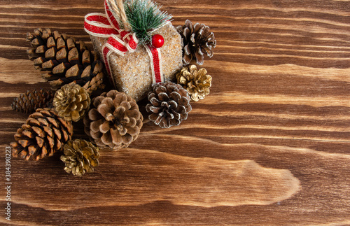 a small gift and a lot of forest cones on a wooden background, a beautiful Christmas and New Year decoration, copy space