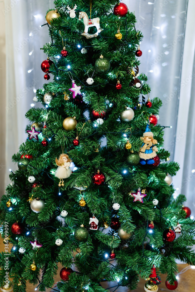Close-up of a festively decorated Christmas tree with toys, balls and garlands.