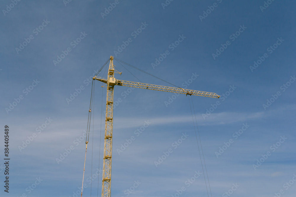 Construction crane on a background of blue sky. Equipment for lifting heavy loads on a construction site. Construction crane on a background of blue sky. Equipment for lifting heavy loads on a construction site.