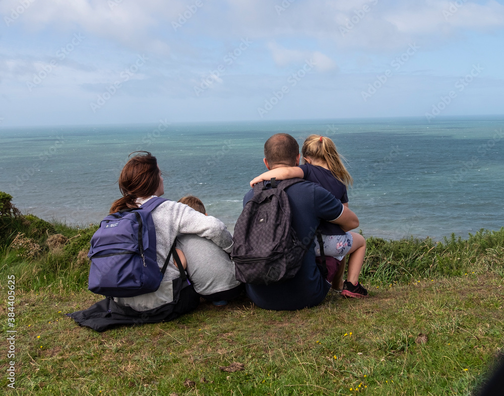 The backview of a  family sitting at the edge of a cliff at Hartland, North Devon.