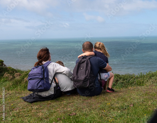 The backview of a family sitting at the edge of a cliff at Hartland, North Devon.