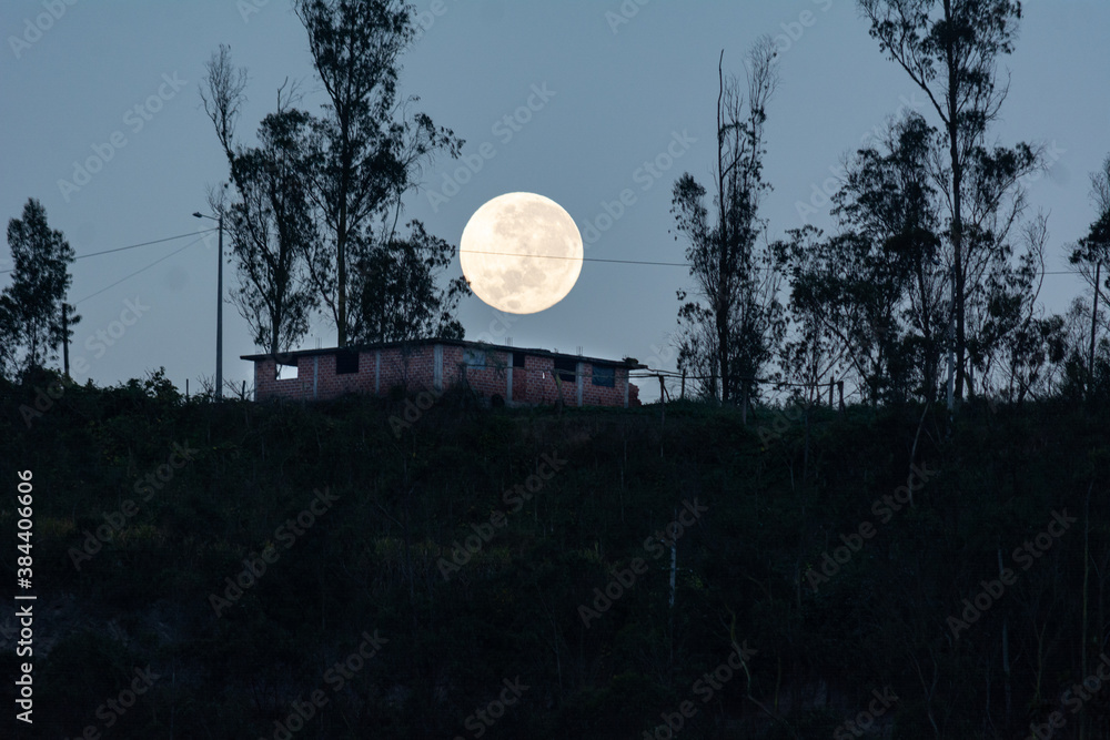 Hermosa luna llena en la montaña sobre una casa