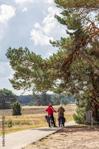 Couple of bikers standing under a tree in National Park De Hoge Veluwe, Gelderland, in he Netherlands