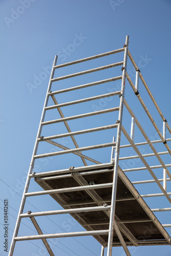 Renovation concept, scaffold tower. Low angle view, vertical, blue sky background.