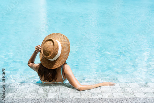 Carefree Asian female relaxing in swimming pool at spa resort. Summer an d holiday concept. Rear view, close up photo