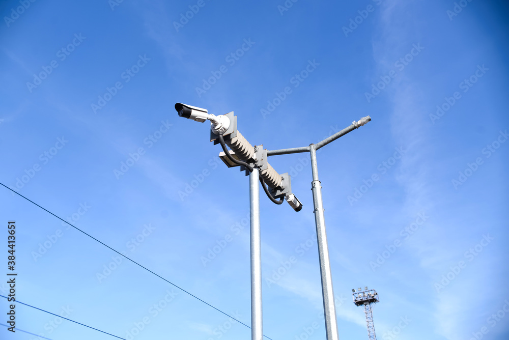 CCTV cameras mounted on a pole, blue sky background. Two video cameras for outdoor surveillance.