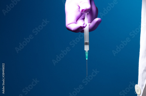 Syringe  medical injection in the hand  palm or fingers. Plastic vaccination kit with needle. Nurse or doctor. Liquid or narcotic drugs. Health care in hospital.Blue background 