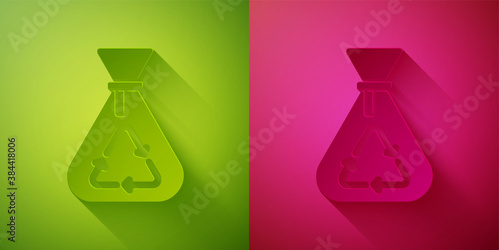 Paper cut Garbage bag with recycle symbol icon isolated on green and pink background. Trash can icon. Recycle basket sign. Paper art style. Vector.