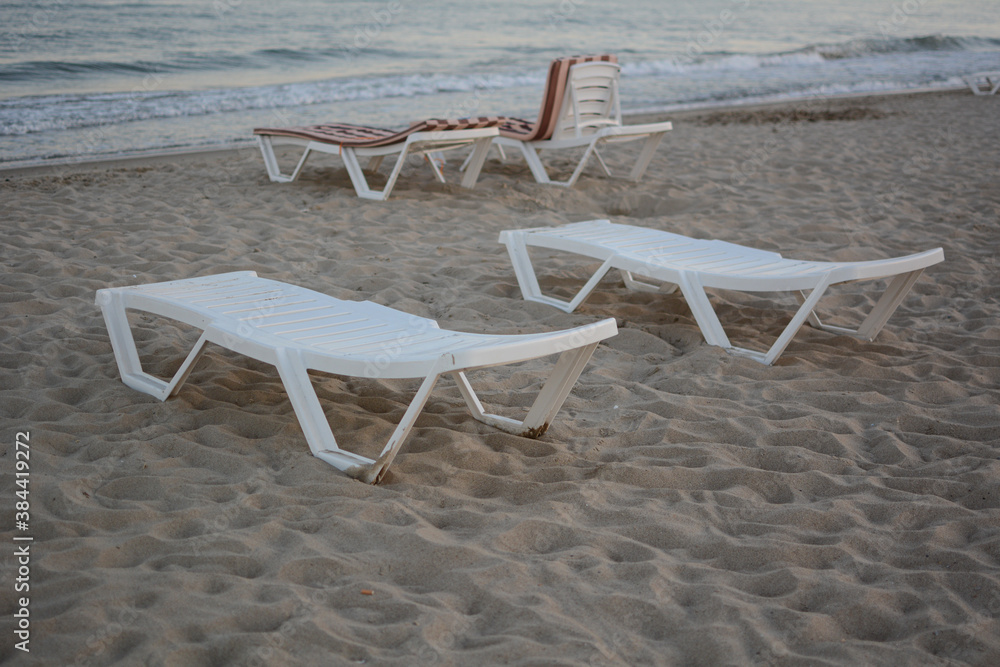 Beach chairs. End of the beach season, plastic beach deck chair on an empty beach at sunset. Beach chairs. End of the beach season, plastic beach deck chair on an empty beach at sunset.
