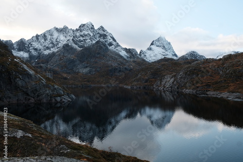 Uninhabited Lofoten Islands during Covid-19 pandemic situation. No tourists and very quiet and peaceful fall mood. Lake with reflection and spectacular mountains covered by fresh snow at the back.