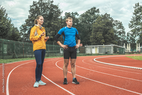 Young Caucasian woman and man observing athletic track while taking a training break