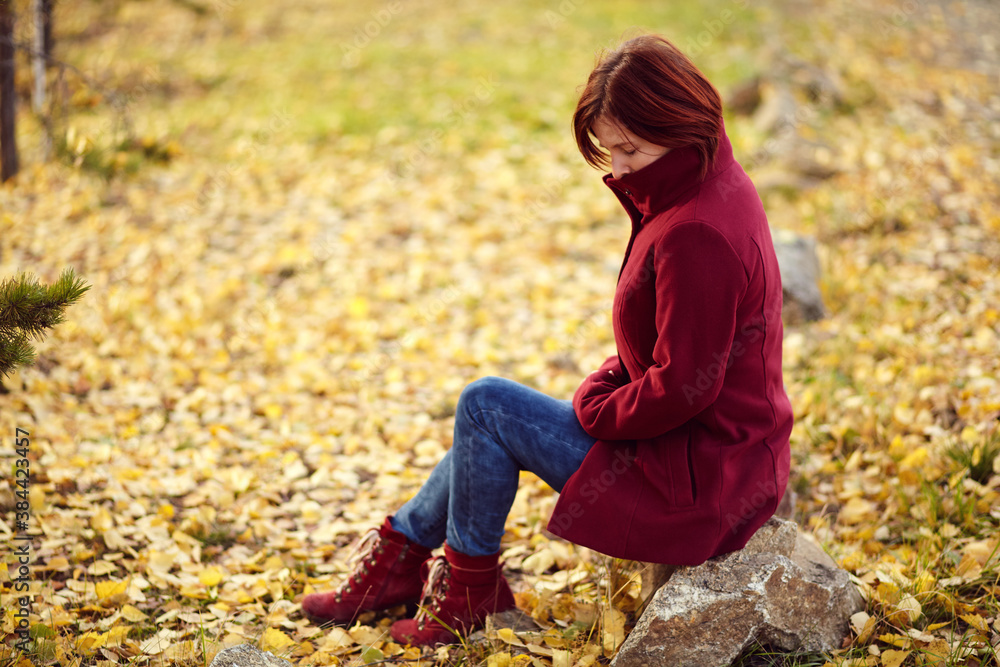 portrait of a sad redhead woman with yellow leaves in autumn. portrait of a sad redhead woman with yellow leaves in autumn.