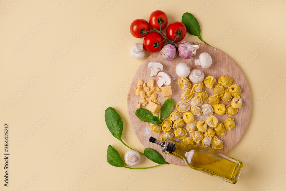 tortellini on a wooden board, tomatoes, mushrooms, spinach. olive oil. Yellow isolated background with copy space. Vegetarian concept tortellini on a wooden board, tomatoes, mushrooms, spinach. olive oil. Yellow isolated background with copy space. Vegetarian concept