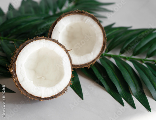 Two halves of coconut and tropical leaves, on a white background. Vegetarianism and healthy eating concept. selective focus