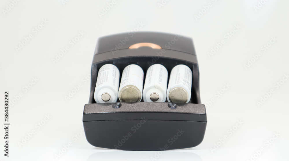 Fast charging of AA batteries. Rechargeable batteries in a black charger with four battery cells on a white background. Fast charging of AA batteries. Rechargeable batteries in a black charger with four battery cells on a white background.