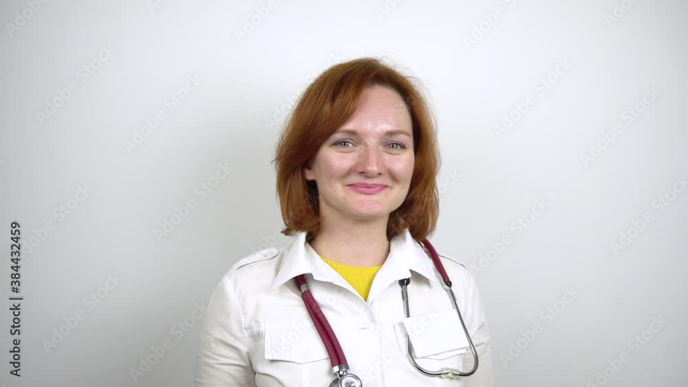 Young female doctor smiling. Portrait of a woman in a medical gown with a stethoscope around her neck.White background. Young female doctor smiling. Portrait of a woman in a medical gown with a stethoscope around her neck.White background.