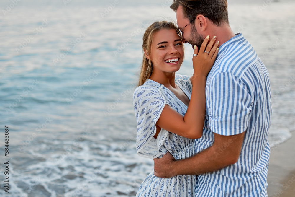 A loving young couple hug on the seashore, enjoying each other and their vacation, romantically spending time on the beach.