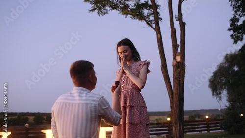 An emotional moment in which a young man asks his girlfriend for marriage. Romantic couple. Concept of marriage applications in nature. Merry me out of the lights. He said yes.