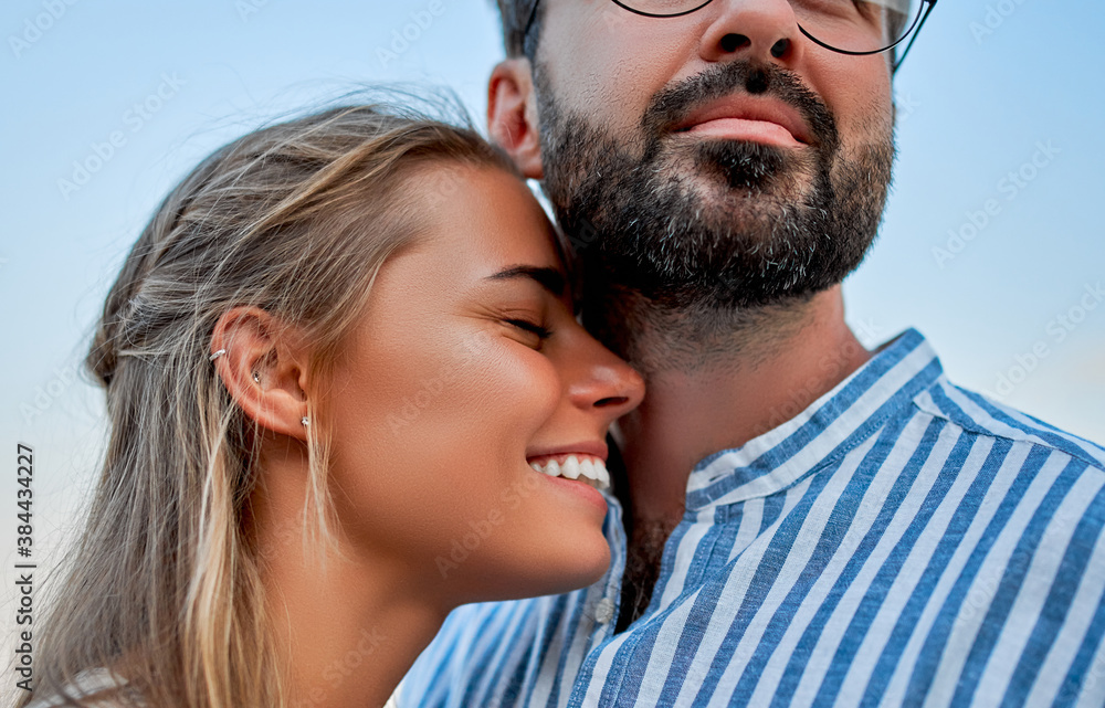 Close-up image of a young couple in love hugging against a blue sky, romantically spending time enjoying each other and their vacation. Close-up image of a young couple in love hugging against a blue sky, romantically spending time enjoying each other and their vacation.