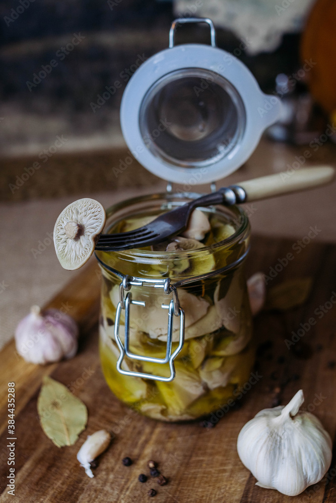 Pickled canned mushrooms in a jar on a cutting Board. Close up. Blurry background. Pickled canned mushrooms in a jar on a cutting Board. Close up. Blurry background.