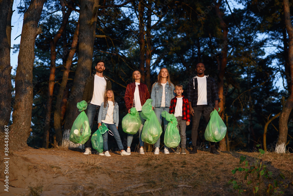Obraz premium Group of young volunteers keep nature clean and picking up the garbage from forest. Society against pollution concept.