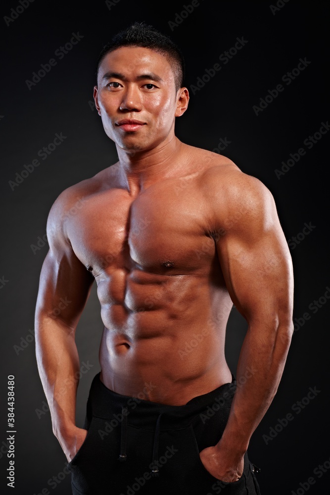 Portrait of muscular asian man against black background.
