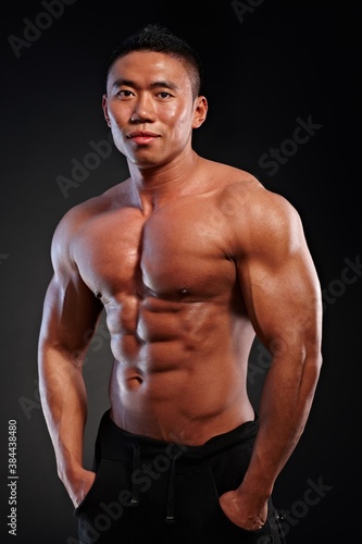 Portrait of muscular asian man against black background.