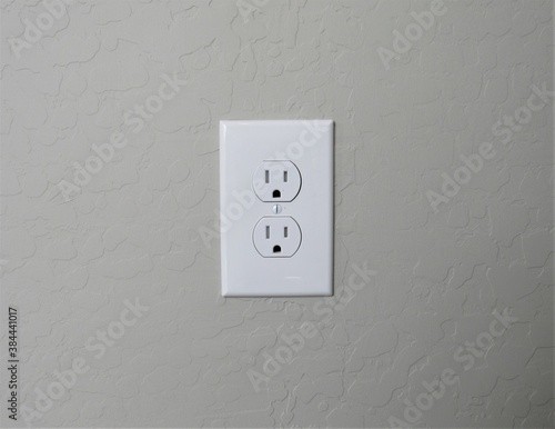 A white American electrical outlet on a stucco wall in southwest America