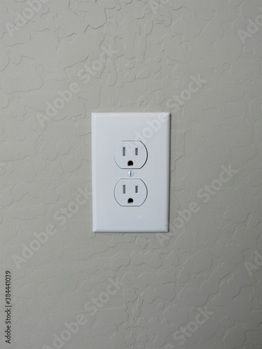 A white American electrical outlet on a stucco wall in southwest America
