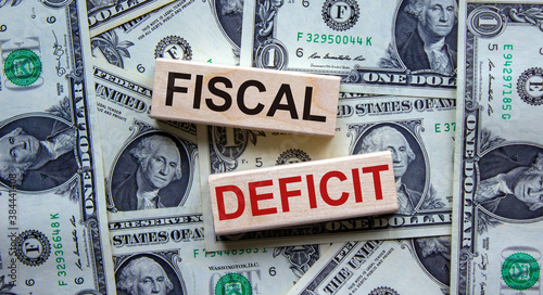 Concept words 'fiscal deficit' on wooden blocks on a beautiful background from dollar bills. Business concept.